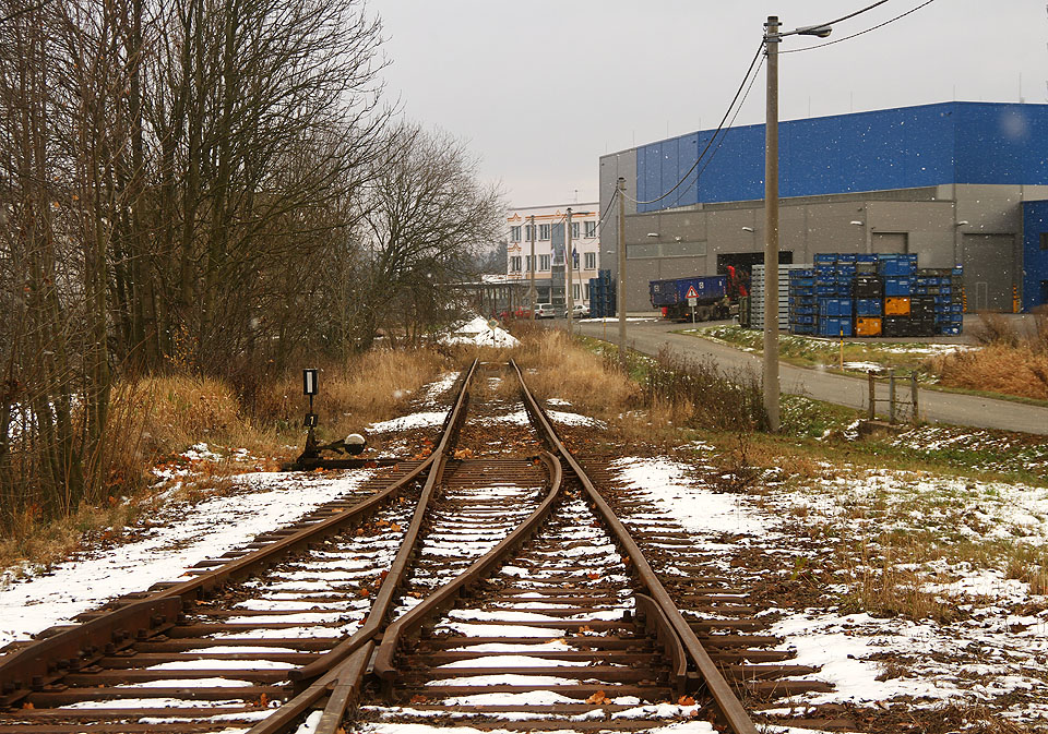 1. staniční kolej pokračuje k jihu jako kolej 1a až do km 16,635, kde je definitivní konec trati. Přestože za koncem koleje v roce 2016 leží rozsáhlý průmyslový areál, existenci vlečky se ani v historii prokázat nepodařilo.