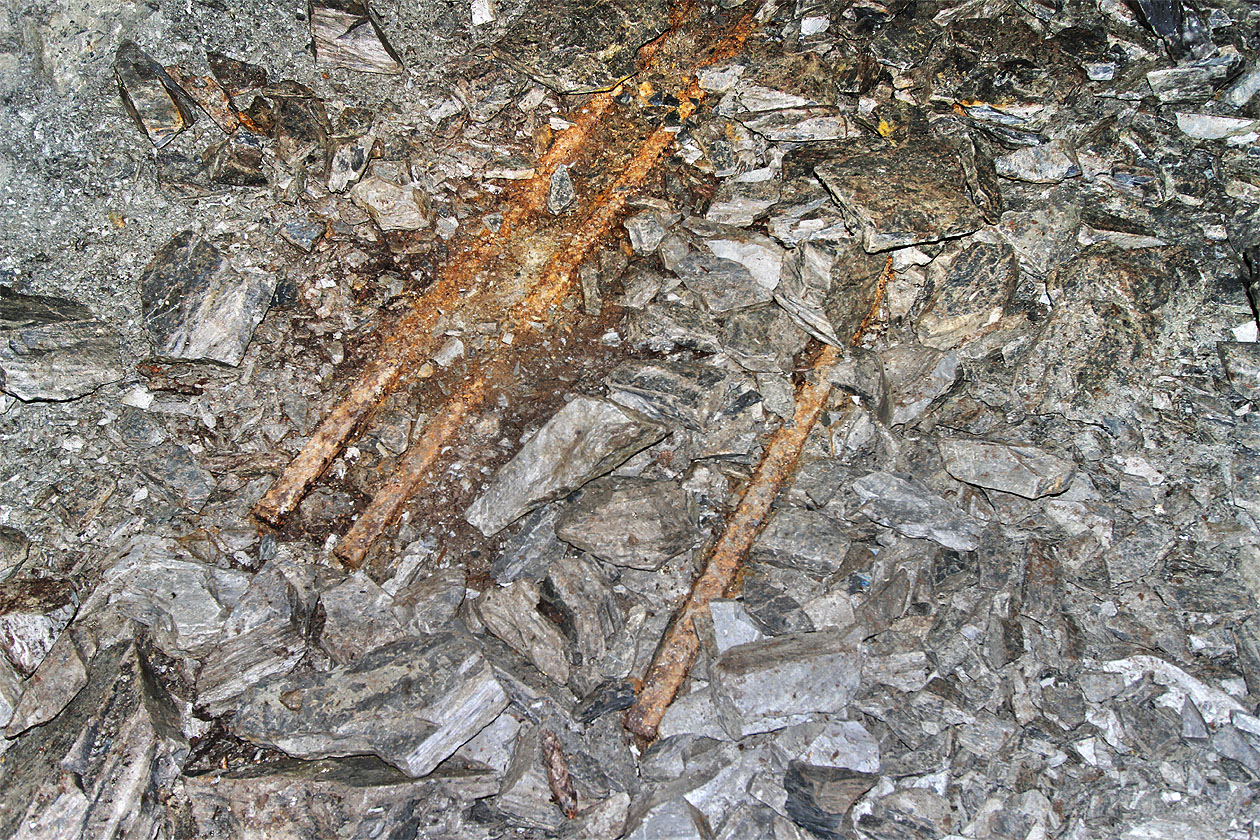 Nejzajímavější nález se však nachází pod hromadou drobného kamení. Po odhrnutí štěrku se objevují rezivé důlní koleje se třemi kolejnicemi ve formě neobvyklé splítky.