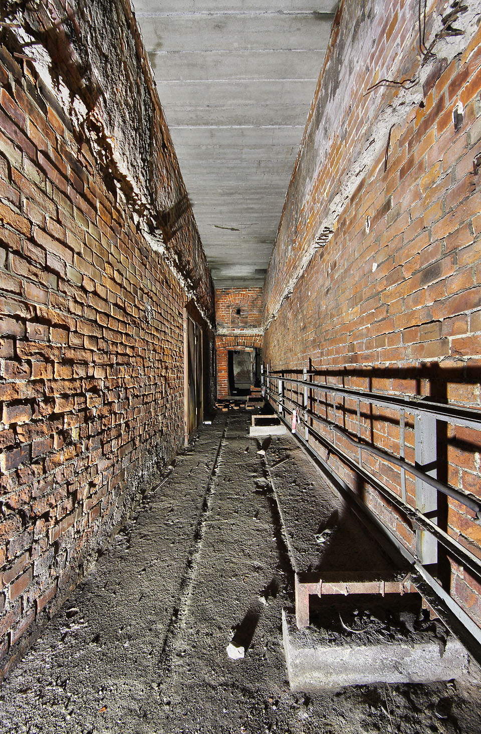 Na některých místech jsou zrezivělé koleje úzkorozchodné drážky patrné už jen díky žlábkům v betonu na podlaze.