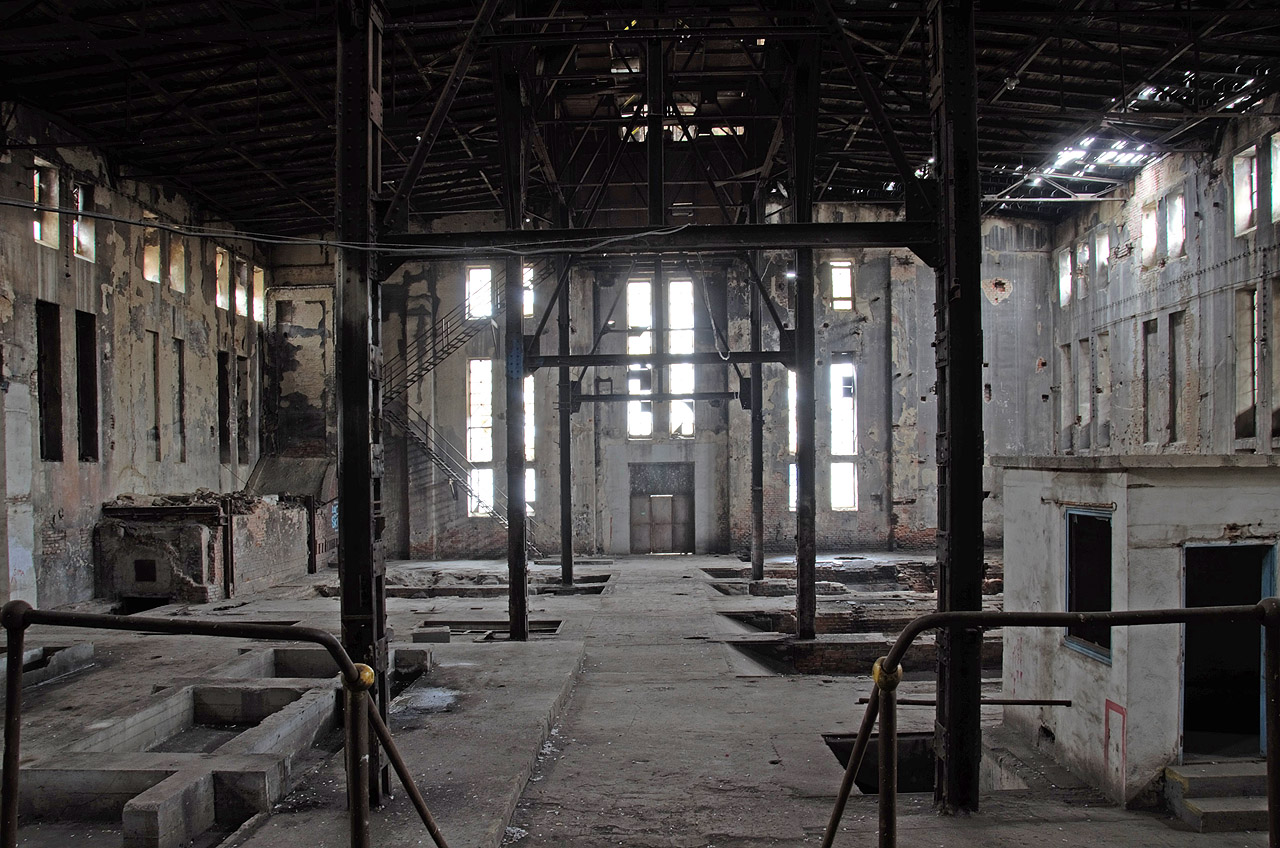 Pohled zevnitř na západní průčelí od strojovny přes výtopnu. Na pravé straně je vidět čtyři otvory na půvdoní čtyři postupně instalované kotle, vlevo vzadu kouřovod a před ním odpopelovací násypky.