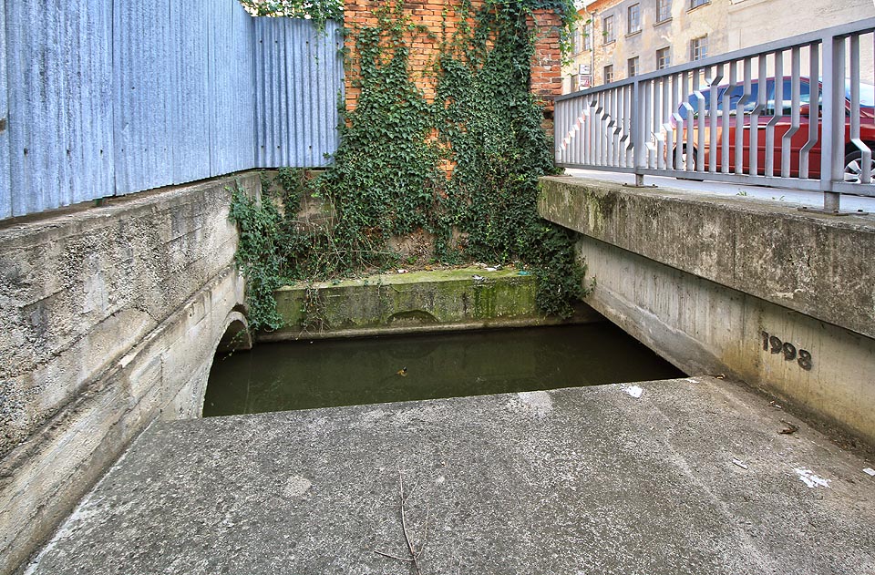 Do prostoru za zábradlím a pod chodníkem lze vlézt. Za povodně tu musí klokotat vodní víry, během normálkního stavu vody však lze sestoupit až k hladině a zklamaně konstatovat, že do prvního tunelu v areálu tepláren se kvůli dvaceticentimetrové škvíře na lodi opět nedostaneme.