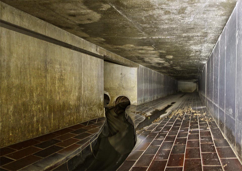 Voda řítící se z ústí trouby se žene až děsivou rychlostí. Není divu, když průtok celého náhonu převádí přes kanalizační přivaděč jen dvojice betonových rour. Naše naěj, že z podzemí vylezeme uvnitř areálu Mosilany jsou vniveč.