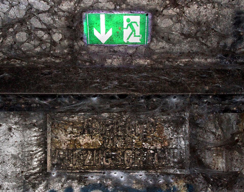 Na jediném místě svítí v tunelu tato zelená tabulka. Stejně jako její rezavějící babička označuje chodbu vedoucí k povrchu, bohužel končící zamčenými dveřmi.