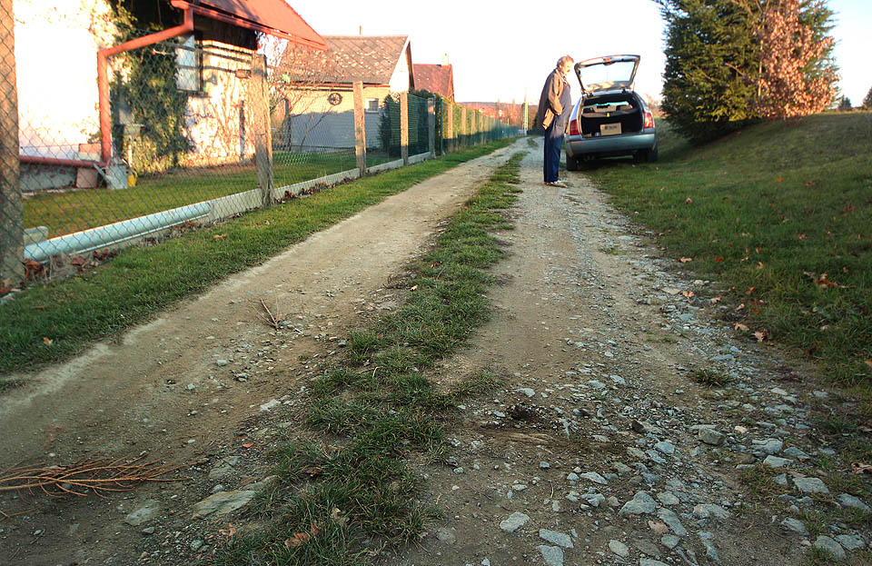 Pozůstatků drážky je v térenu poskrovnu, při troše úsilí se nám podařilo vykopat alespoň zbytky dřevěného pražce. Starousedlík na snímku nám potvrdil, že jde skutečně o součást koleje, která tu byla zavezena štěrkem a sutí. Zavzpomínal taky na doby, kdy okolo projížděly úzkokolejné vláčky.