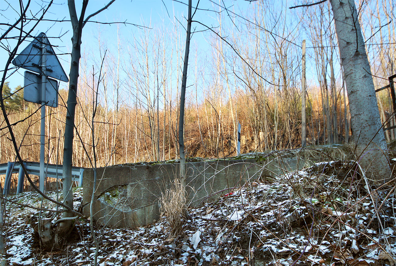 Betonový základ spodního pilíře mostu je těsně pod silnicí dobře patrný dodnes. Nad ním, vedle plastového patníku prosvítá základ druhého pilíře (již nad silnicí).