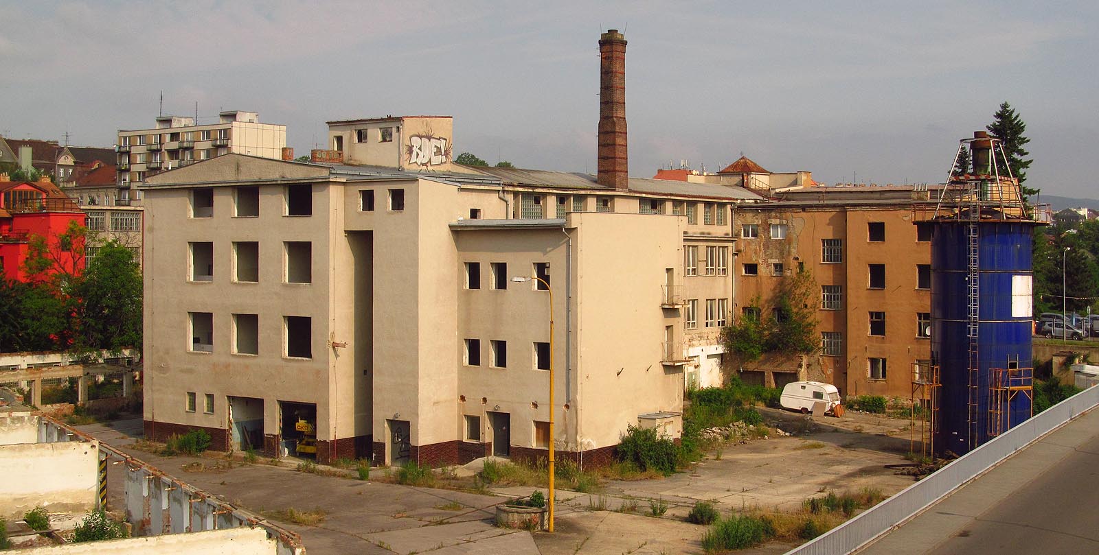 V roce 2014 ještě stály mohutné budovy nábytkářské továrny Tusculum. Východní dvě koleje úzkokolejky vedou před otvory po vratech (v jednom otvoru stojí jeřáb z ČKD) a končí pod zdí se zábradlím v pravém dolním rohu snímku. Rozpoznat je lze zejména podle plevele, který je obrůstá. Západní dvě koleje se skrývají za budovou na snímku vlevo.