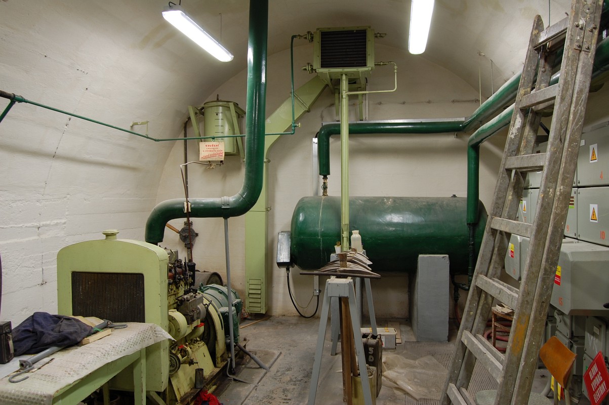 Generátorovna a elektrická rozvodna krytu. Zde by se v případě jaderného útoku vyráběl po dobu několika hodin proud pro osvětlení, filtroventilaci a čerpání vody z vlastní studny pod krytem. Splodiny by se pod tlakem vypouštěly ven.