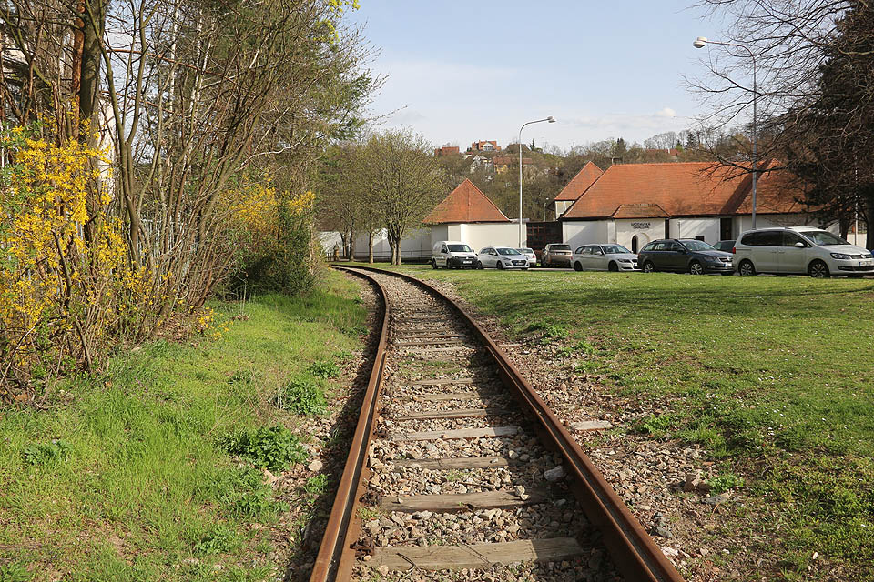 Po krátkém úseku s klasickými kolejnicemi ve čtvrté části vlečky přechází před křížením s Křížkovského ulicí vlečka opět na žlábkové kolejnice. V dálce na stráni domečky Kamenné kolonie.