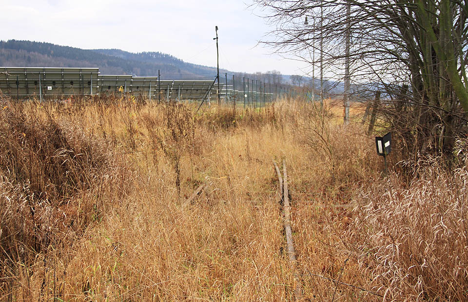 Koleje kdysi pokračovaly dál na manipulační plochu v závodě. Stavitelé solární elektrárny se však vlečkou vůbec nezabývali, prostě ji zahrnuli zeminou a postavili na ni panely.