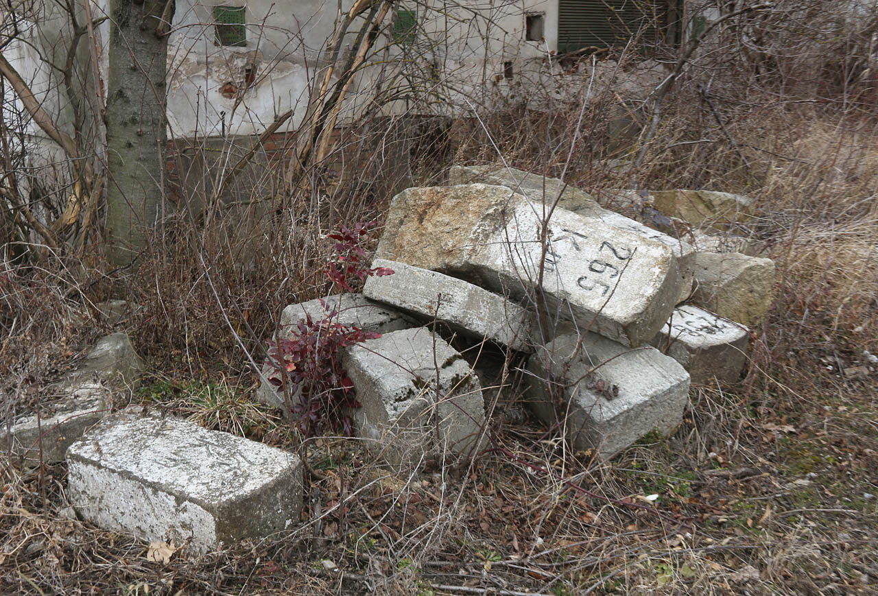 Hromada kilometrovníků a hektometrovníků na místě zteřelé nákladové rampy sýpky.