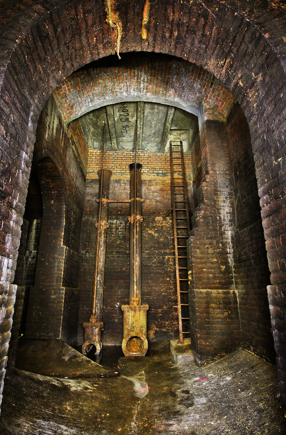 Výtoková šoupata v prvním vodojemu. Otevírání/uzavírání se ovládalo ocelovou tyčí z domku stojícího na povrchu nad poklopem, voda přepadala do nálevky pod stropem.