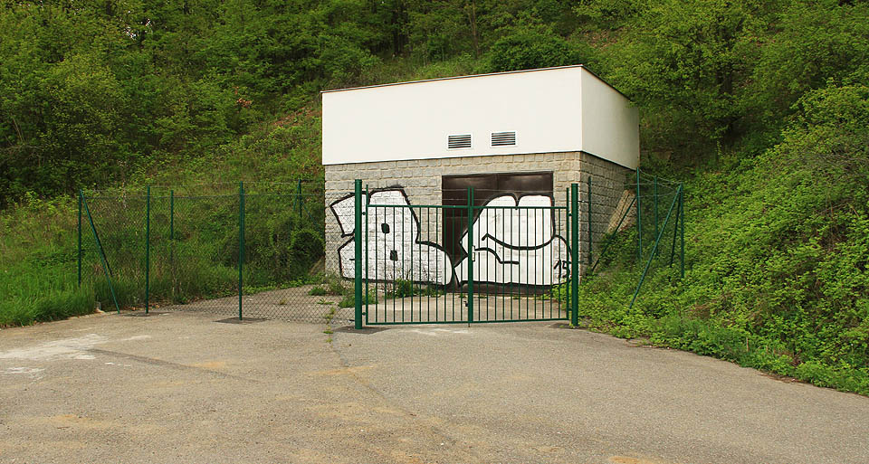 Jižní portál nejdelšího brněnského tunelu kryje nenápadná technická budova, stylem zapadající do stavebního slohu brněnských vodáren v posledním půlstoletí.
