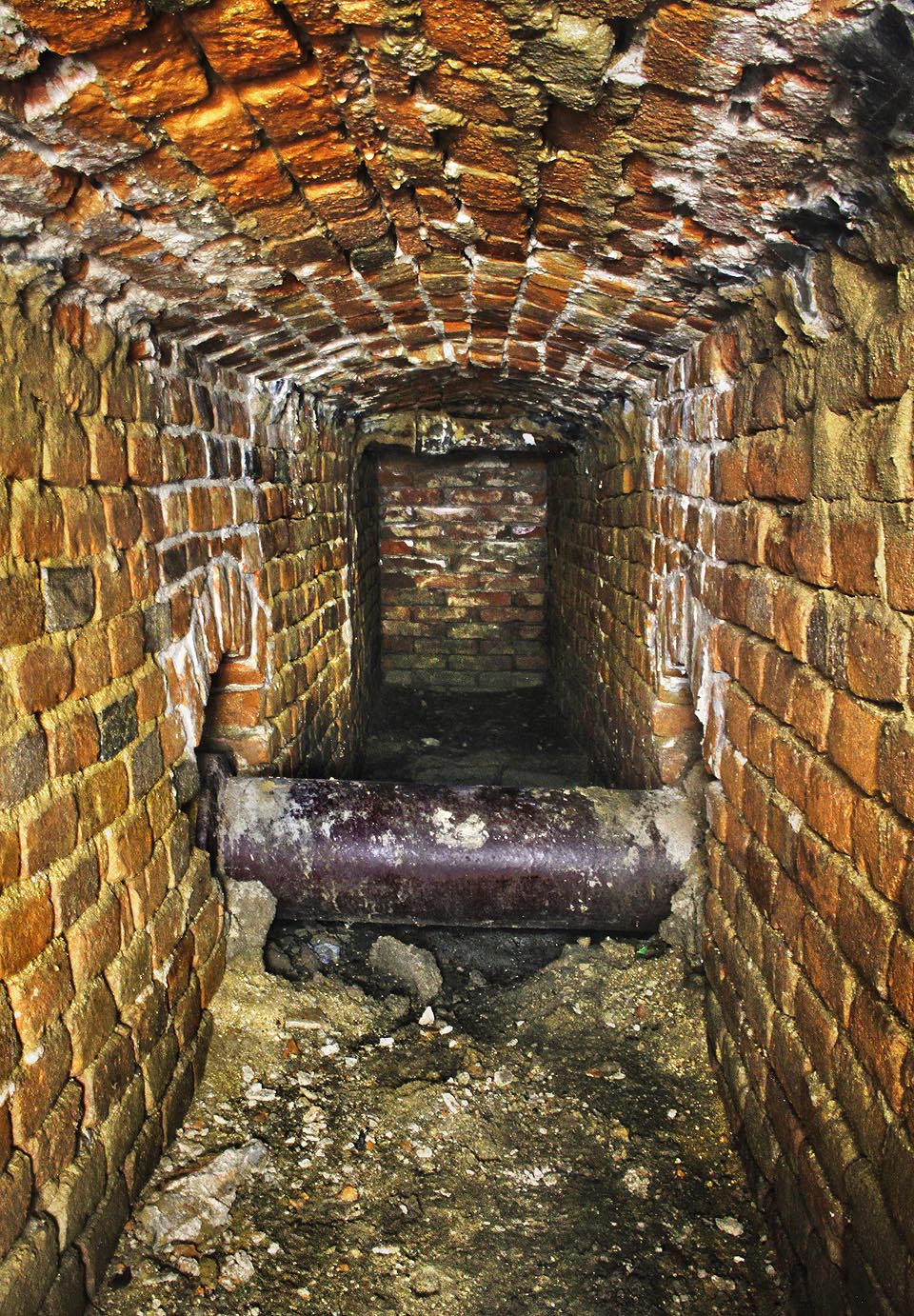 V dolní části zachovalého úseku protíná štolu kolmo moderní kameninová kanalizační roura. V pozadí je vidět relativně čerstvá zeď, ze kterou štola pokračovala až přímo pod kamennou nádrž kašny.