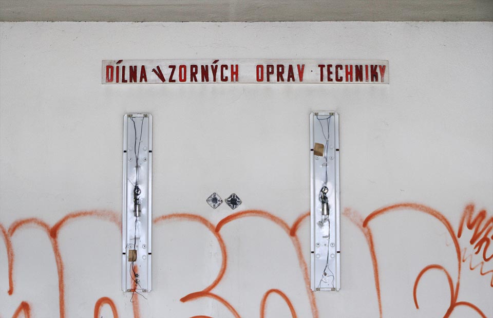 Stěnu zde zdobí nápis „dílna vzorných oprav techniky“.