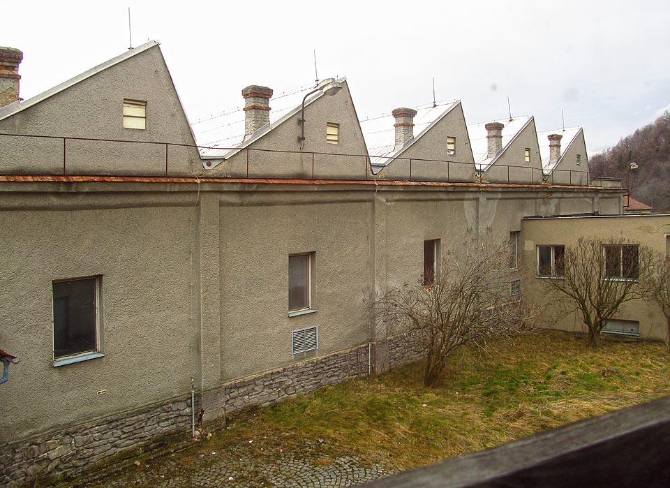 Pohled zpátky přes dvůr na historickou část tkalcovny. Starosvětský ráz přebila hliníková střecha, moderní okna a omítky z Brizolitu.