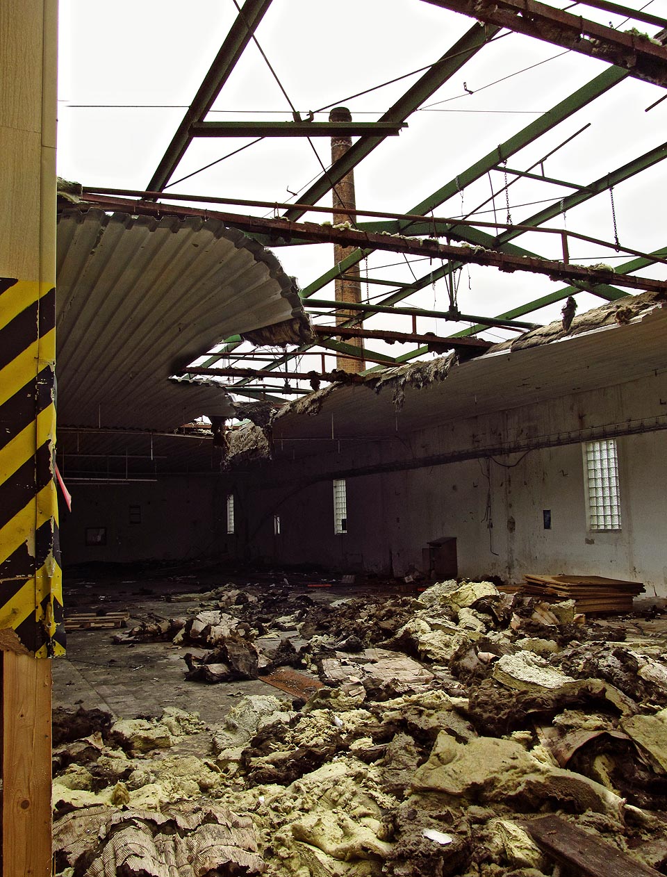 Tovární komín smutně shlíží na spoušť pod sebou. Žel i jeho čas se zanedlouho naplní.