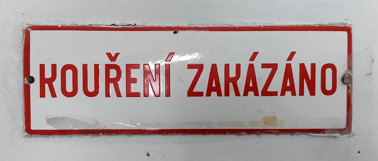 Kouření zakázáno. Poněkud redundantní cedulka, protože kouření je na dráze již roky zakázáno automaticky a všude. Ale aspoň je krásná.